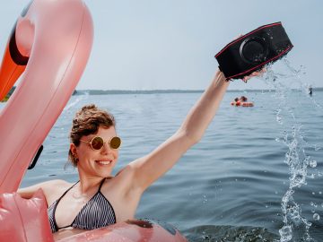 Frau im See mit Luftboot und Bluetooth-Speaker