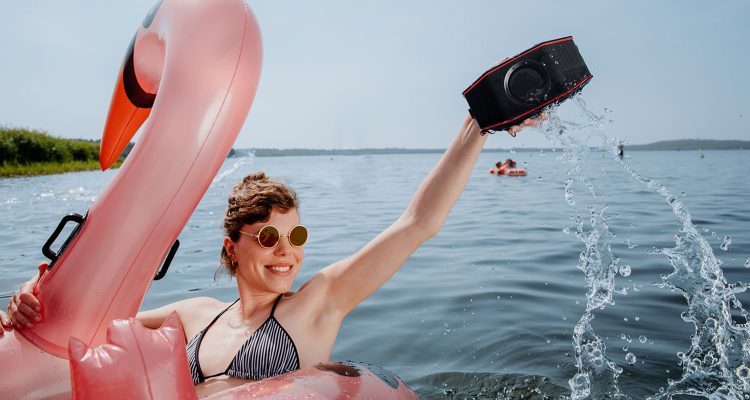 Frau im See mit Luftboot und Bluetooth-Speaker