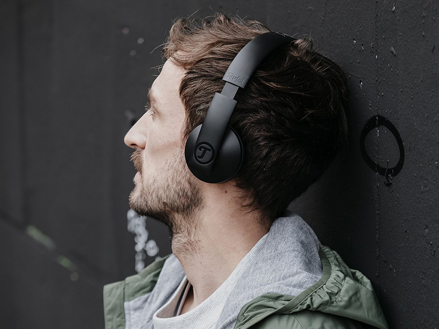 Mann hört an einer Wand über Kopfhörer Musik