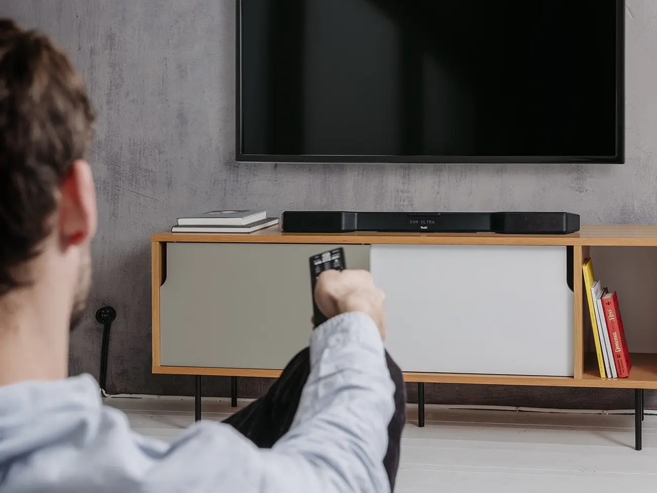 Mann auf Sofa vor Fernseher und Cinebar