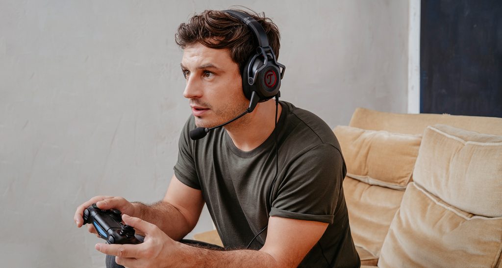 Mann trägt CAGE Gaming-Headset und hält eine Konsolensteuerung in den Händen