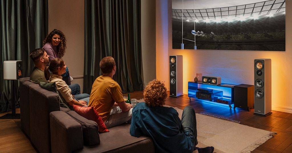 Personnes visionnant un match de Rugby dans un salon avec un système home cinéma Teufel Ultima 5.1