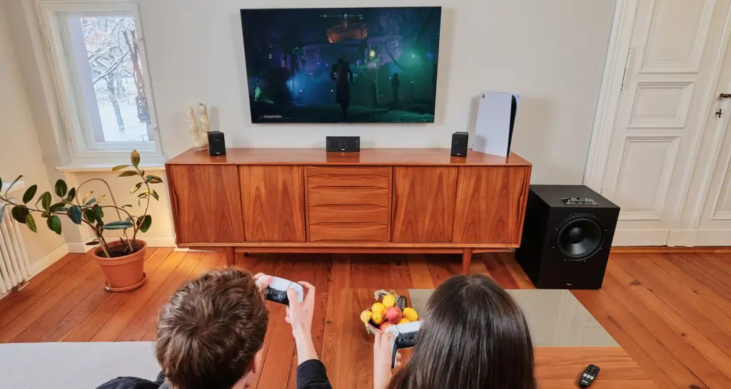 Wohnzimmer mit zwei Personen, die auf der PS5 spielen.