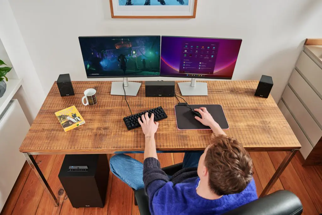 Mann am Gaming-PC mit Surround-Lautsprechern.