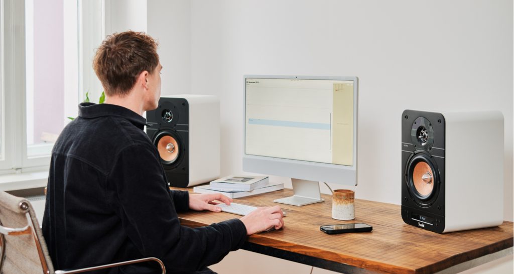 homme travaille sur son ordinateur sur son bureau avec un café et les enceintes ULTIMA 25 ACTIVE