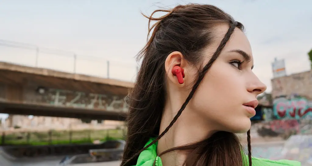 AIRY TWS 2 Junge Frau in urbaner Umgebung trägt In-Ears AIRY TWS 2 in Rot