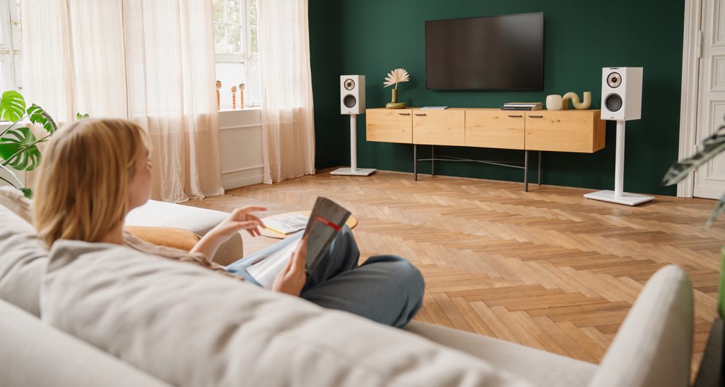 Femme écoute de la musique sur son canapé, dans son salon avec les enceintes STEREO M2 de Teufel