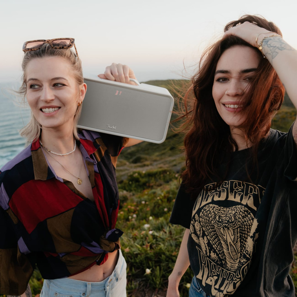 2 amies avec le sourire en plein air écoute de la musique avec l'enceinte Bluetooth BOOMSTER