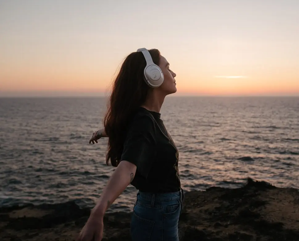 femme thérapie sonore au bord de la plage bras écartés, casque teufel